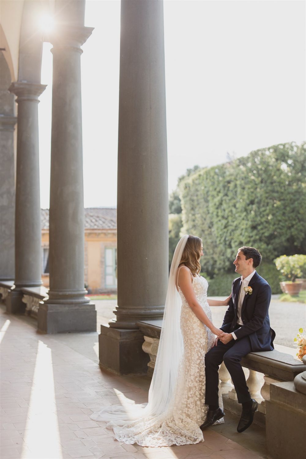 Bride and groom under colonnade of villa in Lucca for wedding receptions