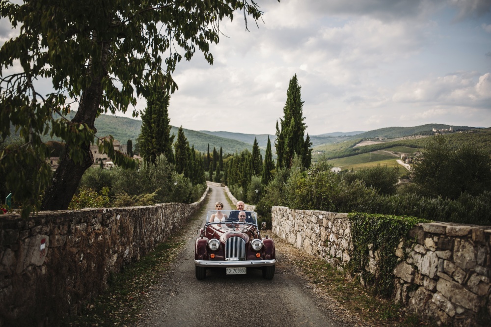 couple arriving with vintage car in a medieval castle in chianti tuscany