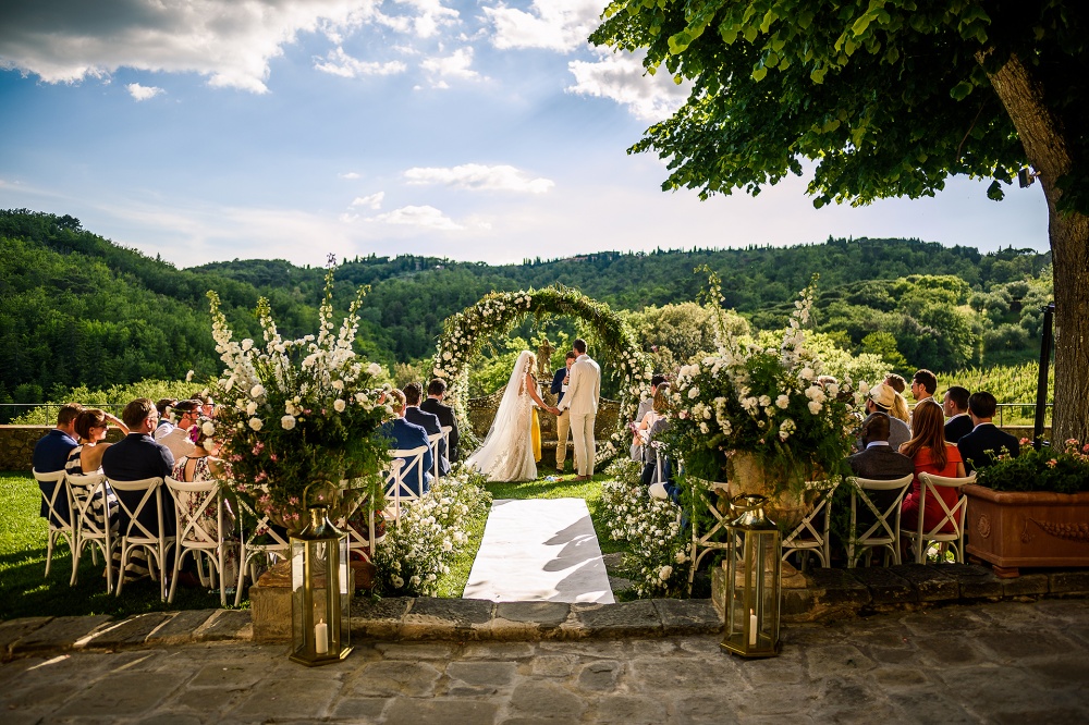 outdoor ceremony in tuscany with a rounded arch with flowers